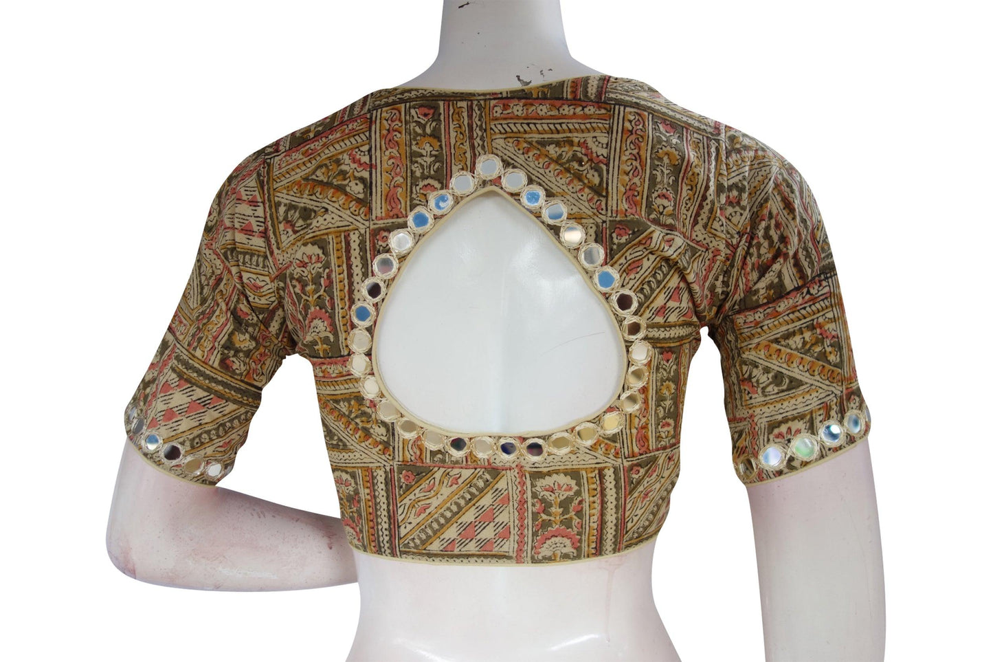 Elevate your ethnic ensemble with our beige Kalamkari cotton blouse, featuring intricate mirror work on the neck and sleeves. This ready-to-wear design effortlessly blends traditional craftsmanship with contemporary style, offering a unique statement piece for any occasion. Experience the charm of Kalamkari artistry in every detail, adding a touch of elegance to your look. Perfect for pairing with sarees or skirts, this versatile blouse is a must-have addition to your wardrobe.